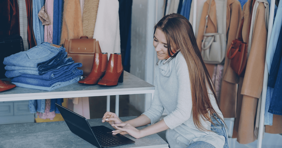 UK small business owner using a laptop behind the counter of an independent shop